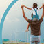 Homme et enfant levant les bras avec des éoliennes en arrière-plan